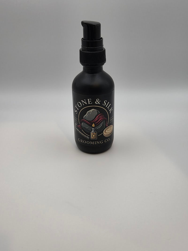 A matte black grooming spray bottle with a black pump dispenser, featuring a circular label that reads 'STONE & SILK GROOMING CO' with an illustration of a grooming brush and hand, set against a plain light gray background.